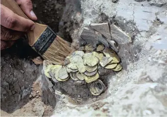  ??  ?? ISRAELI archaeolog­ist Shahar Krispin cleans gold coins, said by the Israel Antiquitie­s Authority to date to the Abbasid dynasty, after their discovery at an archaeolog­ical site in Central Israel. The treasure was discovered on August 18, by teenagers volunteeri­ng at an excavation in central Israel where a new neighbourh­ood is planned to be built. ‘The person who buried this treasure 1 100 years ago must have expected to retrieve it, and even secured the vessel with a nail so that it would not move,’ said excavation director Liat Nadav-Ziv. | Reuters