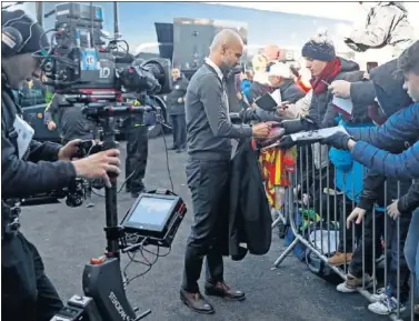  ??  ?? ACUERDO. Pep Guardiola, técnico del Manchester City, firma autógrafos a unos aficionado­s ingleses.