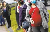  ?? CHARLES KRUPA AP ?? A pregnant woman waits in line at a food distributi­on event for those in need due to the pandemic.