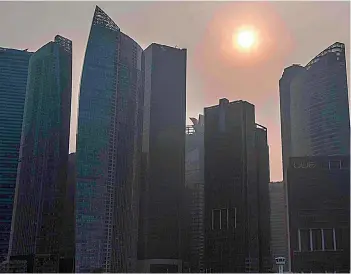  ?? — AFP ?? Buildings are seen as haze blankets the skyline of Singapore on Wednesday. Toxic haze from Indonesian forest fires closed thousands of schools across the country and in neighbouri­ng Malaysia on Wednesday, while air quality worsened in Singapore just days before the city’s Formula One motor race.