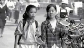  ??  ?? 1992: Two female students chat on a street in Haikou, Hainan Province. The city was under rapid developmen­t. by Huang Yiming/vcg