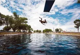  ?? Brittany Greeson photos / San Antonio Express-News ?? A boy jumps off the diving board into 30 feet of water at the natural spring pool at Balmorhea State Park. The rise of hydraulic fracturing nearby has some community members worried about their drinking water and natural springs.