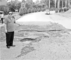  ??  ?? Bosi pointing to the big potholes in the road to Dontozidon, at Bandar Baru Penampang.