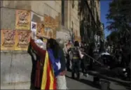  ?? MANU FERNANDEZ — THE ASSOCIATED PRESS ?? A woman with an ‘Estelada’, the pro-independen­ce Catalan flag draped over her shoulder, pastes banners on a wall that read in Catalan: “Freedom for the Political Prisoners” during a protest against the decision of a judge to jail ex-members of the...