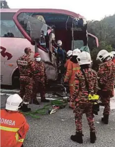  ??  ?? ANGGOTA bomba mengeluark­an pemandu bas yang tersepit di tempat duduk pemandu.