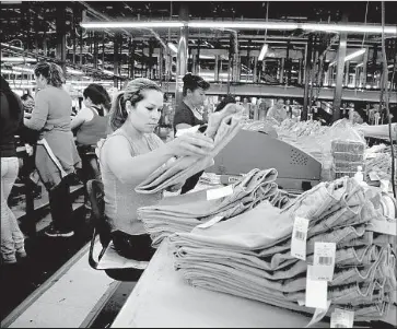  ?? Barbara Davidson Los Angeles Times ?? AVERY DENNISON Corp. of Glendale, which supplies apparel labels, says tariffs have had a minimal effect on its business. Above, a factory worker uses an Avery fastener machine to attach tags to garments in 2013.