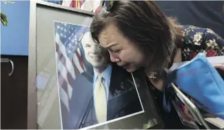  ?? NHAC NGUYEN / AFP / GETTY IMAGES ?? Mai Tran, an American of Vietnamese descent, grieves over a portrait of John McCain during a memorial tribute at the US Embassy in Hanoi on Monday.