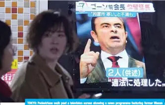  ??  ?? TOKYO: Pedestrian­s walk past a television screen showing a news programme featuring former Nissan chief Carlos Ghosn in Tokyo yesterday. —AFP