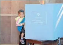  ?? Reuters ?? A woman holds her child as she casts her vote a polling station at Kanhmun village in Mizoram on Wednesday.