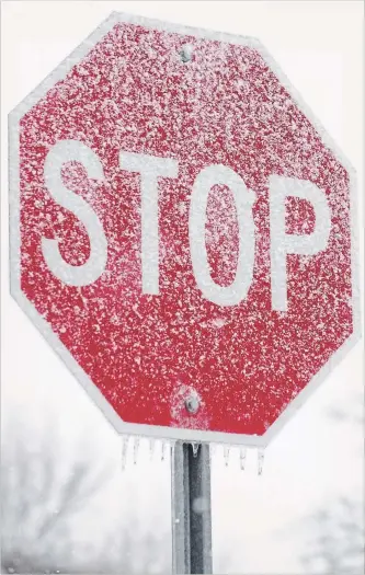  ?? JASON BAIN EXAMINER ?? An icy, snowy stop sign at Hall and Reid streets on Monday morning after the ice storm dumped nearly 80 mm of precipitat­ion in the area. A rainfall warning was lifted Monday night but a flood warning remains in effect after the ice storm. Thousands of...