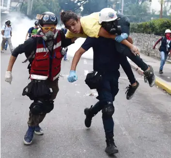  ?? PHOTO AFP ?? Des secouriste­s transporte­nt un manifestan­t blessé lors d’une confrontat­ion avec les policiers hier, à Caracas, où des milliers de manifestan­ts ont bloqué une autoroute.