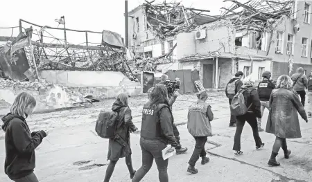  ?? ?? Periodista­s caminan por las calles de una ciudad recuperada por Ucrania
