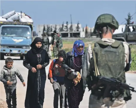  ?? AFP ?? Displaced Syrians arrive at the Russian-manned Abu Al Duhur checkpoint from rebel areas in Idlib province bound for government territory. Near Damascus, convoys take fighters and families out of besieged neighbourh­oods to other insurgent held areas