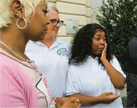  ?? KENNETH K. LAM/BALTIMORE SUN ?? Taylor Hines, 21, right, an ambassador for Healing Youth Alliance, wipes away tears after speaking at a rally Tuesday outside City Hall. Also pictured are Donna Bruce of the Trauma-Informed Care Task force and Kyla Liggett-Creel, director of Healing Youth Alliance.