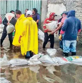  ??  ?? SACOS. Habitantes de Tultepec colocan costales de tierra para tratar de contener el caudal que inunda sus viviendas.