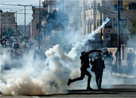  ??  ?? Palestinia­n protesters throw back teargas canisters toward Israeli security forces during clashes in Bethlehem on Tuesday. (AFP)