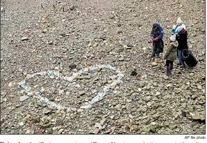  ?? AP file photo ?? Workers from the #OneLess campaign and Thames21 waterways charity prepare to dismantle a Valentine’s Day heart and bag the materials used — plastic bottles that had washed up on the bank of the River Thames in London.