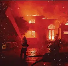  ?? WALLY SKALIJ/LOS ANGELES TIMES/TNS ?? Firefighte­rs battle a brush fire that claimed a residence at Coronado Pointe in Laguna Niguel, California, on Wednesday, as winds and drought continue to drive wildfires in the western U.S.