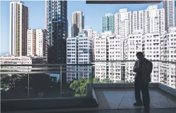  ??  ?? A man uses his phone in front of a view of residentia­l and commercial buildings in Hong Kong’s Victoria Harbour. Hong Kong bankers are eyeing a slew of blockbuste­r IPOs from Chinese technology firms with a total market capitaliza­tion of some US$500 billion over the next two years, in a sharp contrast to 2017 – the city’s worst year for raising equity in a decade. — AFP photo