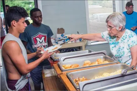  ?? WILLIAM HARVEY/RIVER VALLEY & OZARK EDITION ?? Nicki Suddeth, right, serves Morrilton football player C.J. Gonzales, 17, while Kyren Gilreath, 17, waits his turn at the free Summer Food Service Program at First Presbyteri­an Church in Morrilton. The program, in its third year, offers free breakfast...