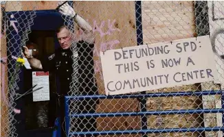  ?? Goran Tomasevic/Reuters ?? ‘Cortando o financiame­nto da polícia de Seattle: isso agora é um centro comunitári­o’, diz placa em frente a prédio da força de segurança da cidade