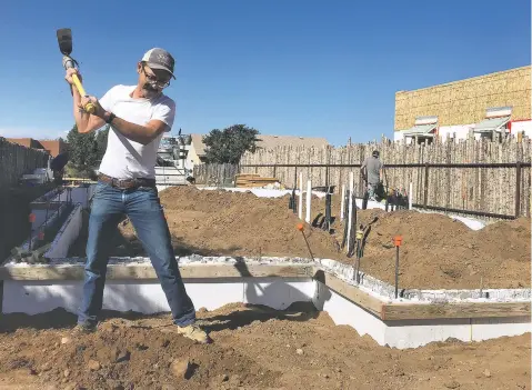  ?? PAUL WEIDEMAN/THE NEW MEXICAN ?? Johnny Gee, a staffer with YouthWorks, swings a pick last week at a Santa Fe Habitat for Humanity homesite in Oshara Village. Twelve years after the subdivisio­n’s grand opening, there are about 110 homes completed in the neighborho­od and a dozen under constructi­on.