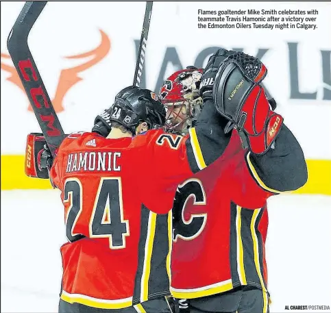  ??  ?? Flames goaltender Mike Smith celebrates with teammate Travis Hamonic after a victory over the Edmonton Oilers Tuesday night in Calgary.