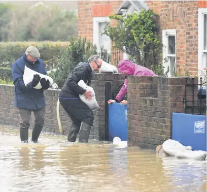  ??  ?? Residents putting out sandbags in Gloucester Road in Tewkesbury; below left, Mark Fox, landlord of the flooded Boat Inn pub at Ashleworth; below right, tackling a flooded Tewskesbur­y on foot