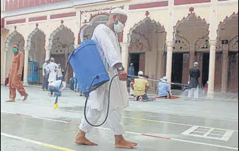  ?? PTI ?? A worker sprays disinfecta­nt as devotees arrive to offer prayers at Jama Masjid in Gurugram.