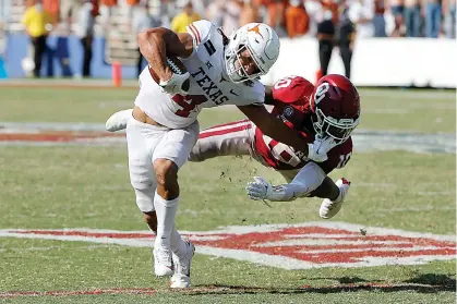  ?? AP Photo/Michael Ainsworth ?? Texas wide receiver Jordan Whittingto­n (4) tries to break a tackle from Oklahoma defensive back Pat Fields (10) during overtime of an NCAA college football game Saturday in Dallas. Oklahoma defeated Texas, 53-45, in four overtimes.