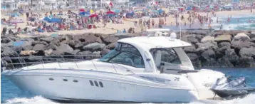  ?? (Photo: AP) ?? A yacht cruises through the Manasquan Inlet as a large crowd fills the beach in Manasquan, New Jersey, on June 28, 2020. With large crowds expected at the Jersey Shore for the July Fourth weekend, some are worried that a failure to heed mask-wearing and social distancing protocols could accelerate the spread of the coronaviru­s.