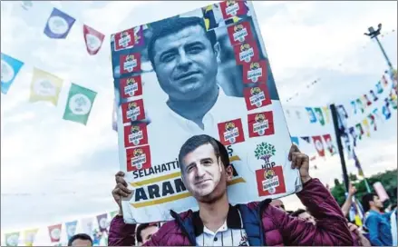  ?? YASIN AKGUL/AFP ?? A supporter of imprisoned Selahattin Demirtas, presidenti­al candidate of the pro-Kurdish People’s Democratic Party, wears a mask of of Demirtas during an pre-election campaign in Istanbul on Sunday.