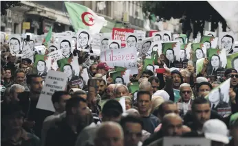  ?? AP ?? Algerian protesters carry photograph­s of political detainees on the streets of Algiers to reject the presidenti­al elections and protest against the government on December 27