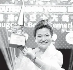  ??  ?? Law receiving her TOYM trophy at the awards night in Penang recently. - Photo courtesy of Esther Law