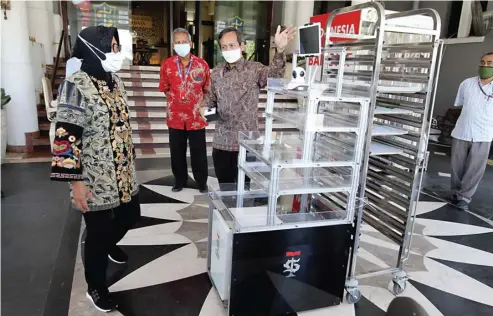  ?? FRIZAL/JAWA POS ?? BERGUNA UNTUK NAKES: Rektor ITTS Tri Arif Sarjono mendemonst­rasikan cara kerja robot pelayanan kepada Wali Kota Surabaya Tri Rismaharin­i kemarin.