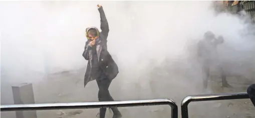  ?? PHOTO VIA AP ?? A student attends a protest at Tehran University where a smoke grenade was thrown by anti- riot police in Iran. The country has seen its largest anti- government protests since the disputed presidenti­al election in 2009.