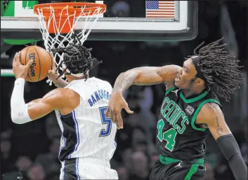  ?? Michael Dwyer The Associated Press ?? Magic rookie forward Paolo Banchero goes to the basket past Celtics center Robert Williams III in Orlando’s victory Friday at TD Garden. Banchero scored 20 points.