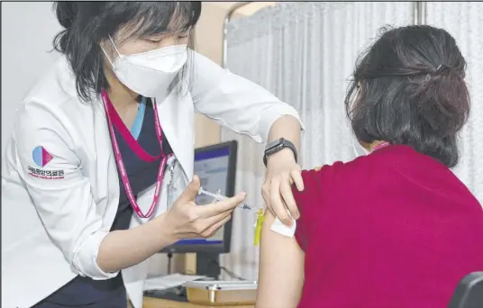  ?? Song Kyung-Seok The Associated Press ?? A medical worker receives a dose of the Pfizer COVID-19 vaccine at a vaccinatio­n center Saturday in Seoul, South Korea.