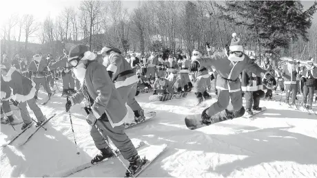  ?? AP Photo/Robert F. Bukaty ?? A snowboarde­r, right, gets a jump start as 160 Santas head down a slope Sunday at Sunday River during the ski resort’s 18th annual Santa Sunday event in Newry, Maine. The Santas raised $2,500 for the Sunday River Community Fund, a fund that benefits...