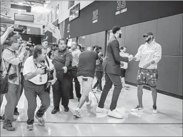  ?? Marcus Yam Los Angeles Times ?? PHOTOGRAPH­ERS SCRAMBLE to get the picture as Anthony Davis greets new teammate and casually dressed LeBron James during a news conference. The two stars helped put the Lakers’ roster together.