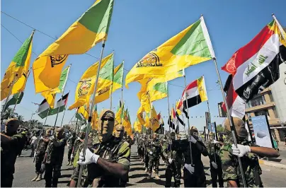  ?? [ AFP ] ?? Aufmarsch der Hisbollah-Brigaden in Iraks Hauptstadt Bagdad. Stützpunkt­e der Miliz wurden nun von den USA bombardier­t.