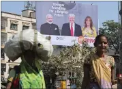  ?? AJIT SOLANKI — THE ASSOCIATED PRESS ?? Women walk past a billboard Thursday in Ahmadabad, India, featuring Indian Prime Minister Narendra Modi, President Donald Trump and first lady Melania Trump.