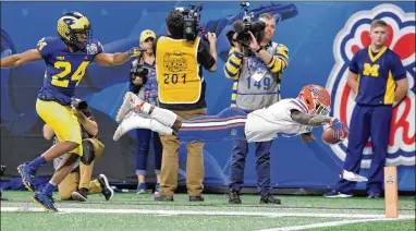  ?? HYOSUB SHIN / HSHIN@AJC.COM ?? Florida running back Kadarius Toney is pushed out of bounds by Michigan’s Lavert Hill in the first half of the Peach Bowl on Saturday. The Gators ran for 257 yards on 40 carries and three touchdowns in the game.