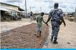  ?? —AFP ?? SOUBRE, Ivory Coast: Police officers detain a child caught drying cocoa in the sun in the village of Opouyo on May 7, 2021 during an operation to remove children working on cocoa plantation­s.