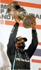  ??  ?? Lewis Hamilton lifts the trophy on the podium on Sunday