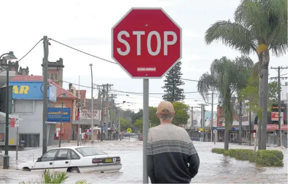  ?? — Reuters ?? A local resident watches as floodwater­s enter the main street of the northern New South Wales town of Lismore on Friday.