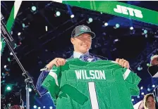  ?? TONY DEJAK/ASSOCIATED PRESS ?? BYU quarterbac­k Zach Wilson holds a New York Jets jersey after beling selected second overall in the first round of the NFL draft Thursday in Cleveland.