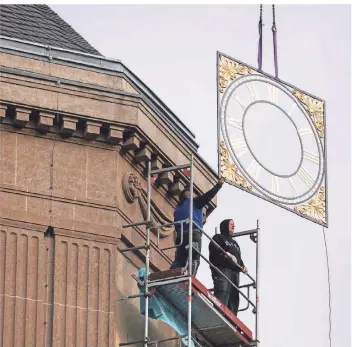  ?? RP-FOTOS (3): LAMMERTZ ?? Feinstarbe­it in 35 Meter Höhe: Die sanierteTu­rmuhr für das Landgerich­t wurde per Kran am Turm platziert. Dort oben herrschte starker Wind.