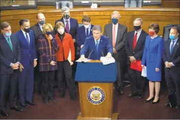  ?? Caroline Brehman CQ Roll Call ?? DEMOCRATIC Sen. Joe Manchin III, center, and a bipartisan group of lawmakers meet in Washington this month to unveil a COVID- 19 relief bill. President- elect Joe Biden praised their work as a model for the nation.