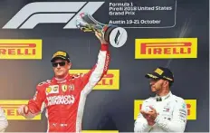  ?? AP ?? Ferrari’s Kimi Raikkonen holds the trophy after winning the US Grand Prix, as Mercedes’ Lewis Hamilton (right) applauds.